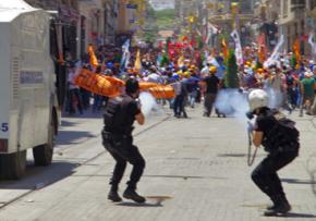 Turkish police fire tear gas into a crowd of protesters on a street near Taksim Square