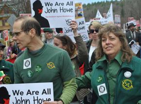 John Howe (left) marches with supporters in a protest defending his job